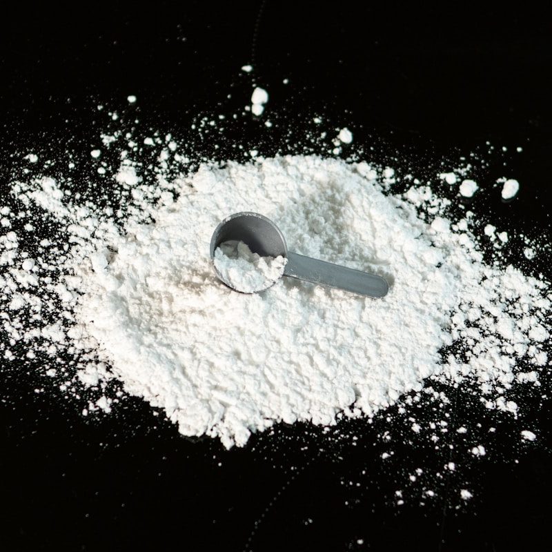 Fine white powder in a measuring scoop — Nu-FLOW organic anticaking agent