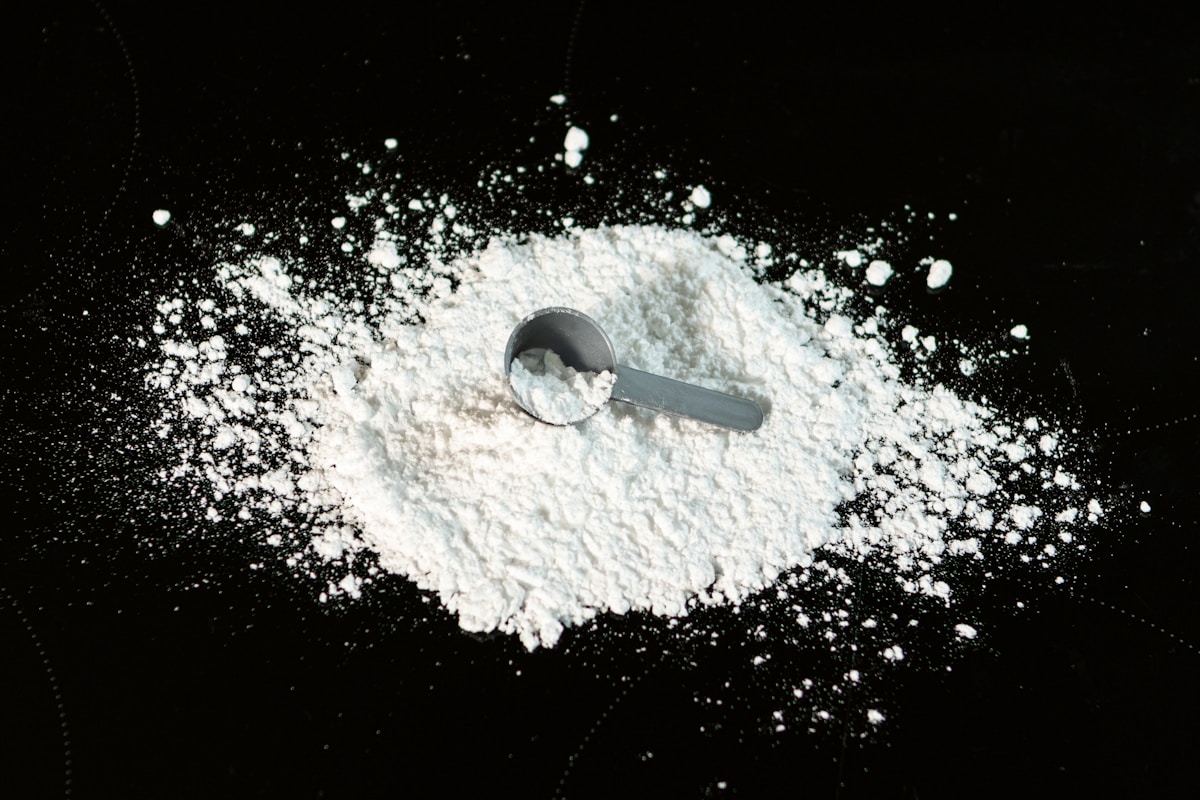 Fine white powder in a measuring scoop — Nu-FLOW organic anticaking agent